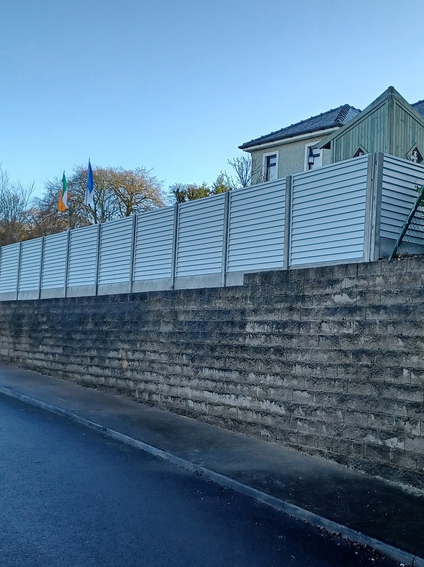 White aluminium louvre roadside boundary fence on a retaining wall in Ballyroan